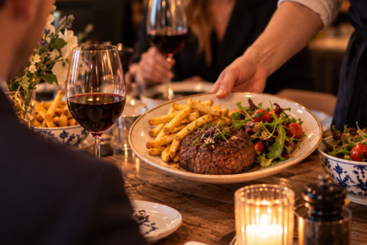 Een hoofdgerecht met friet en salade wordt aan tafel geserveerd bij Knus